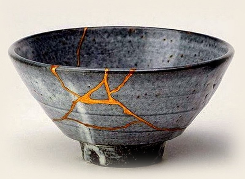 A grey ceramic bowl repaired with gold along its cracks.